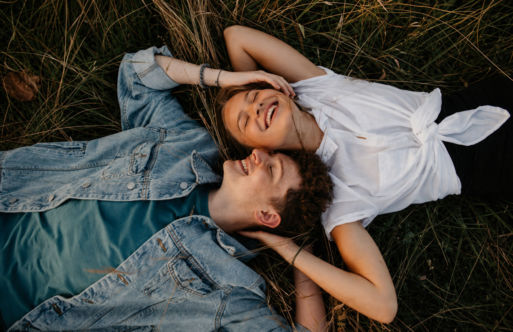 Couple Lying In Grass Laughing, Top-Down View